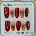 SkyMarie small press-on nails: red & gold gradient with rhinestones, silver bows, and solid red accents.