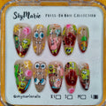 SkyMarie large Spongebob press-on nails with cartoon characters, clear-to-red ombre, and gold studs.