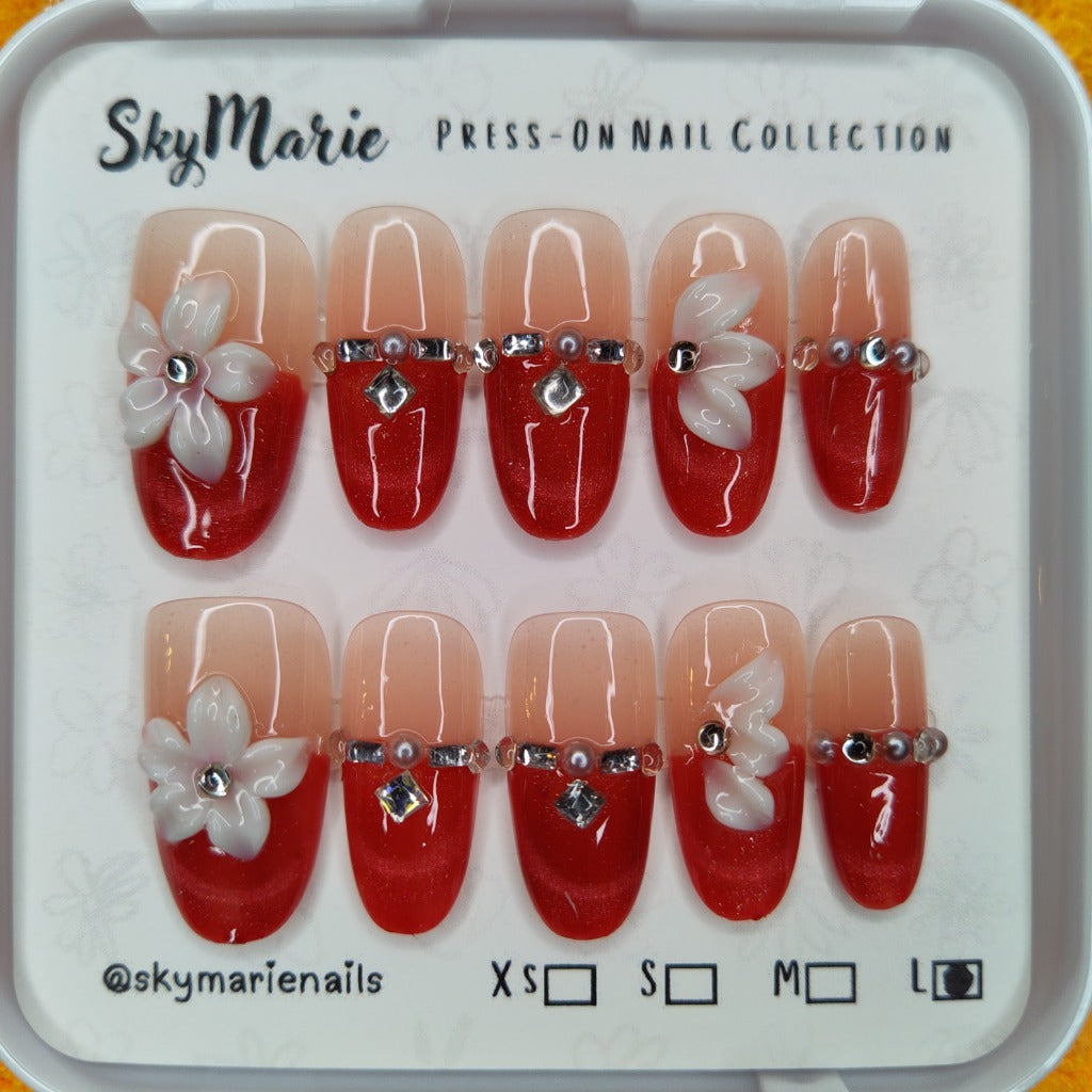 Large SkyMarie red & nude ombre press-on nails with 3D white flowers, rhinestones, and pearls.