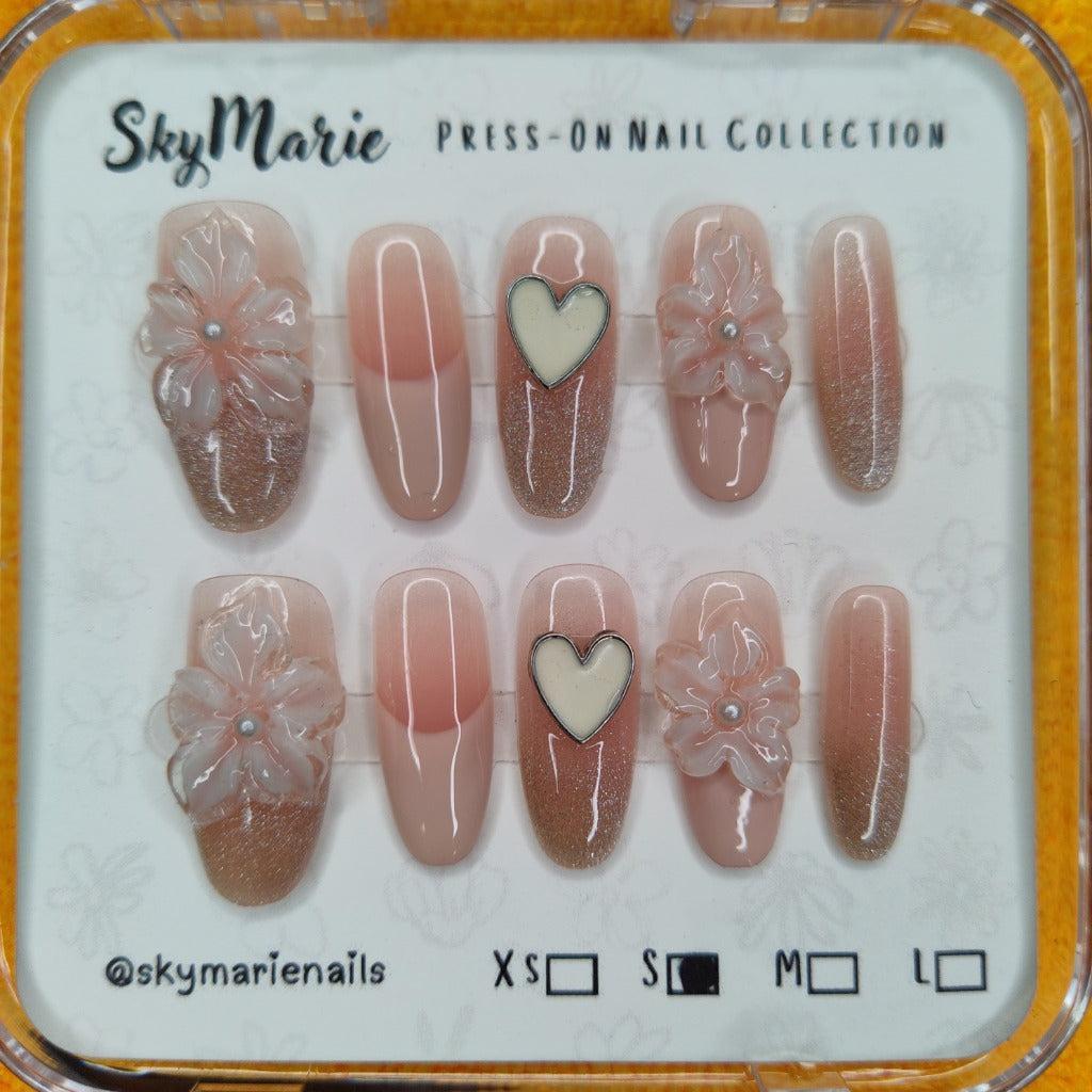 SkyMarie small nude press-on nails with 3D floral, heart, and glitter ombré designs.