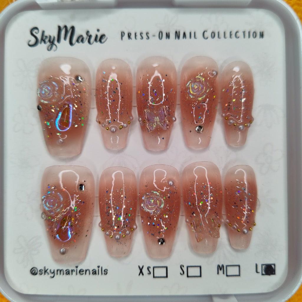 SkyMarie handmade large press-on nails with glitter ombre, 3D rose & butterfly charms, pearls, and rhinestones.