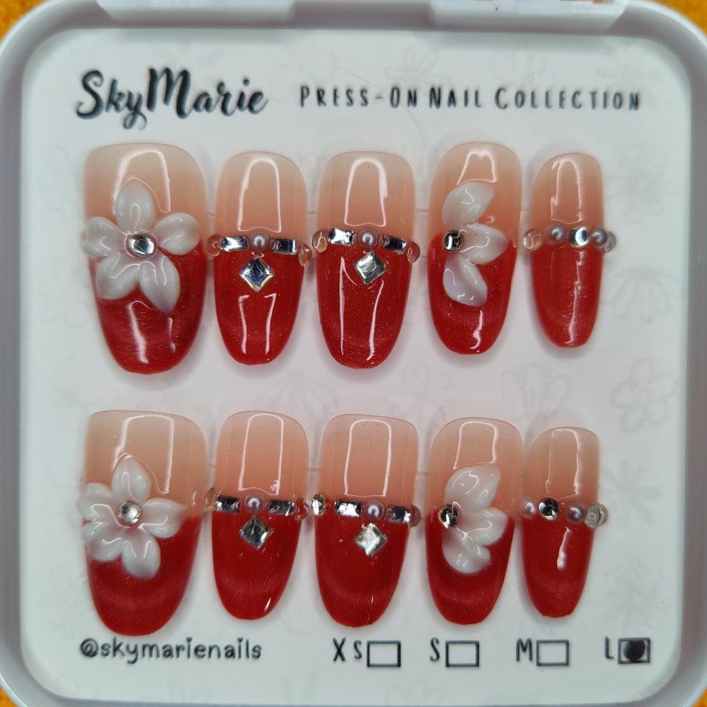 SkyMarie large red ombre press-on nails with 3D white flowers and silver rhinestones.