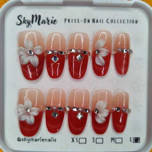 SkyMarie large red ombre press-on nails with 3D white flowers and silver rhinestones.