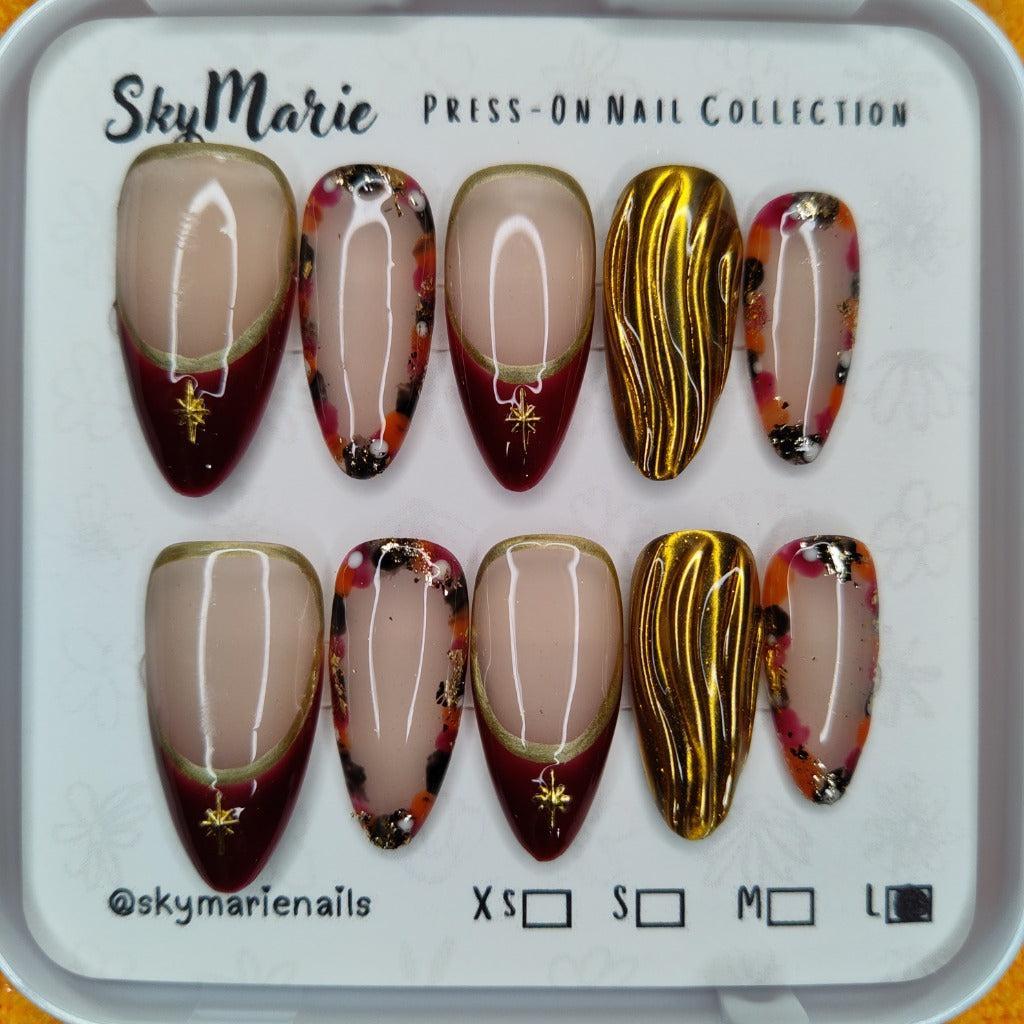 SkyMarie large press-on nails: red French tip, gold metallic wavy, and tortoise design with flakes.
